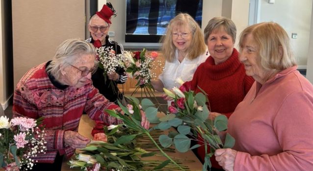 Group of five women arranging flowers