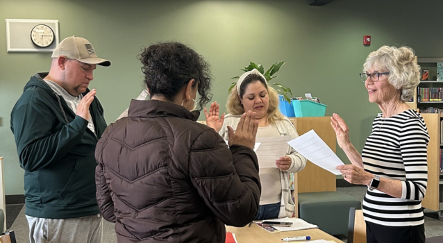 Group of four adults practicing taking citizenship pledge